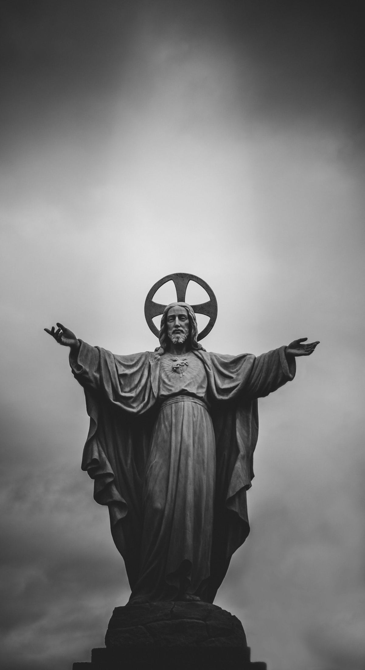 Black-and-white photograph of a statue of the Sacred Heart of Jesus, with arms open, illustrating the New Testament covenant and sacrament, 99 Sheep Co.